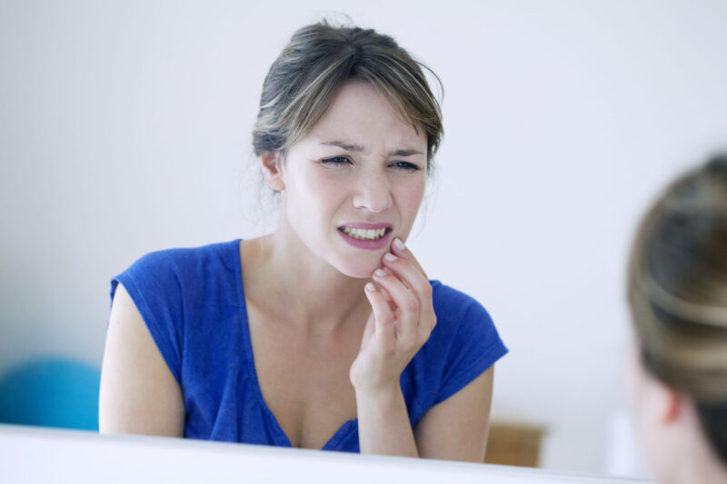 A woman in pain from clenching her teeth together