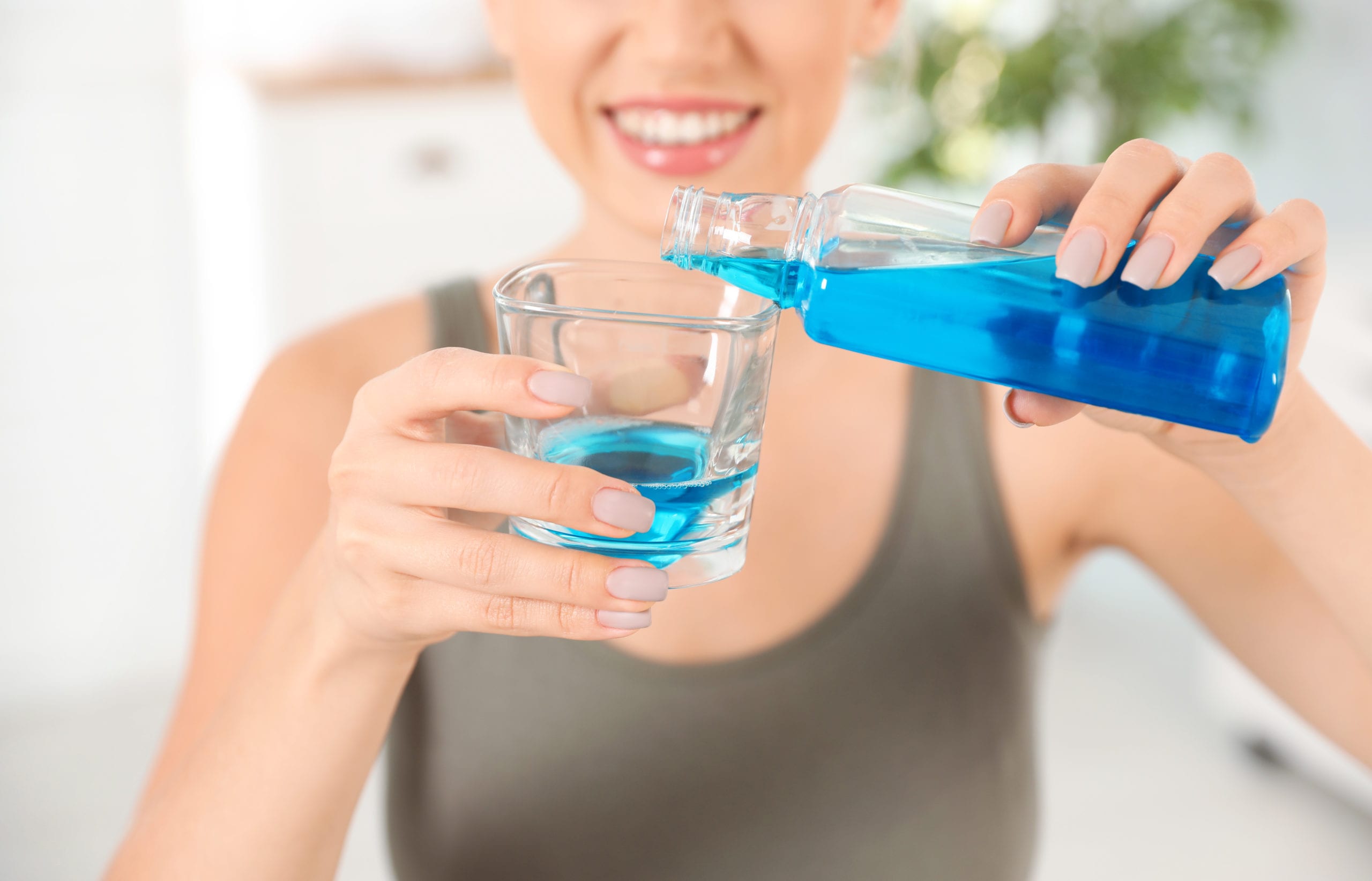 woman pouring mouthwash into glass