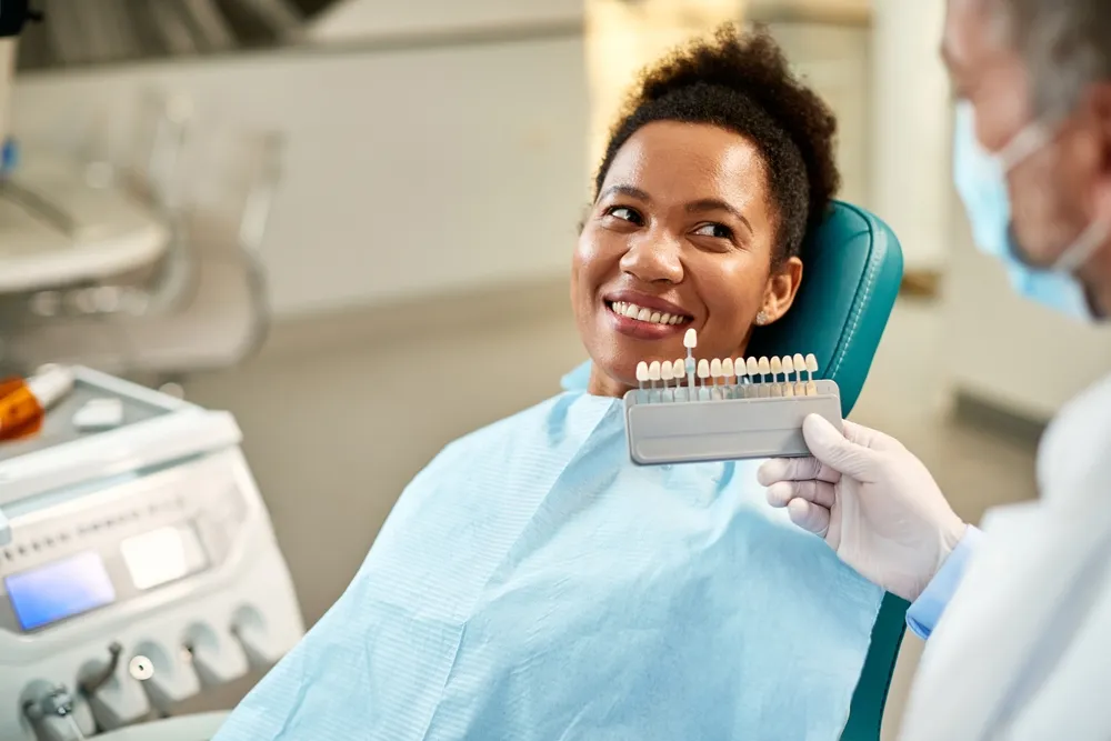 A woman smiles while seated in a dentist chair, conveying a positive dental experience.